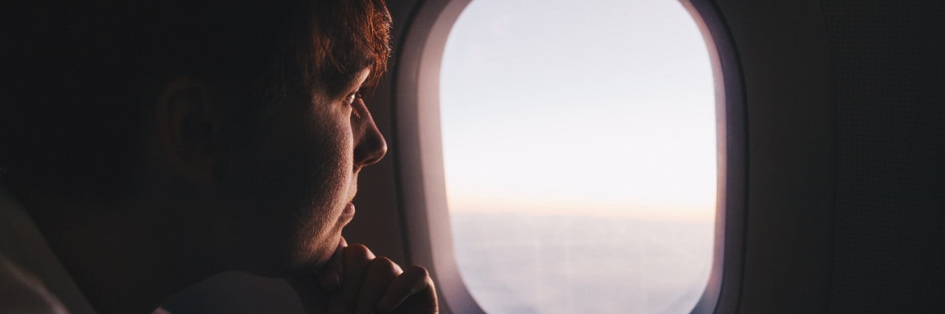 man thinking while looking through plane window